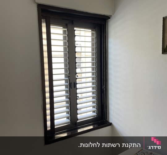 חלון עם תריסי אלומיניום בחדר מואר